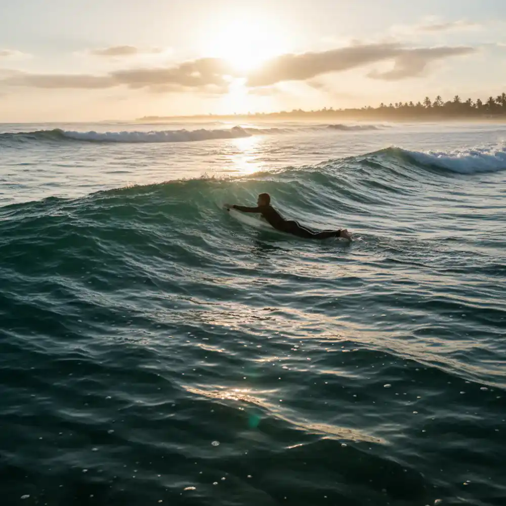 Surfer paddling out to green waves